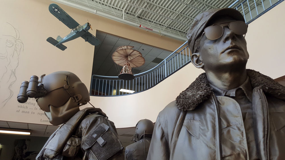 Statues of two pilots facing opposite directions inside the U.S. Army Aviation Museum.